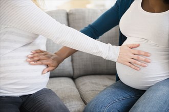 Pregnant women feeling stomachs of each other