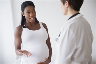 Black pregnant woman talking to doctor