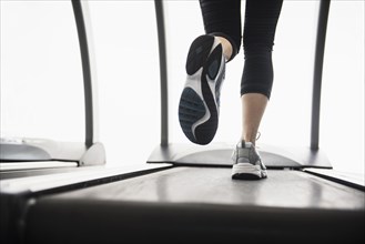 Legs of mixed race woman running on treadmill