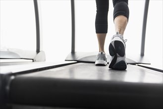 Legs of mixed race woman walking on treadmill