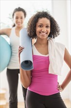 Woman carrying yoga mat in exercise class