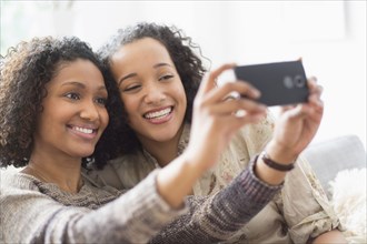 Smiling women taking cell phone photograph