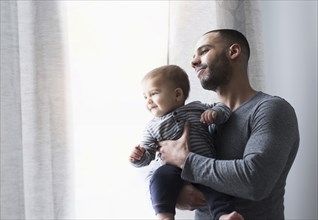 Smiling father and baby son looking out window