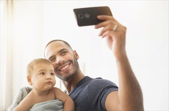 Father taking cell phone photograph with baby son