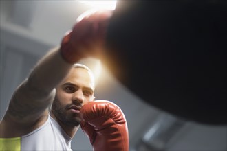 Close up of Hispanic man punching bag in gym