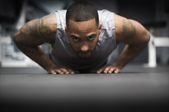 Hispanic man doing push-ups in gym