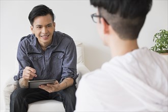 Men using digital tablet in living room