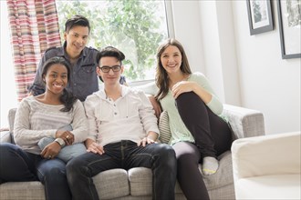 Smiling friends sitting on sofa