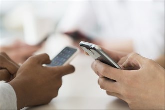 Close up of friends texting with cell phones at table