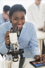 Scientist using microscope and digital tablet in research laboratory