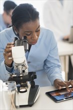 Scientist using microscope and digital tablet in research laboratory