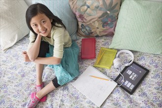 High angle view of Chinese girl doing homework on bed