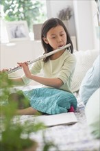 Chinese girl practicing flute on bed