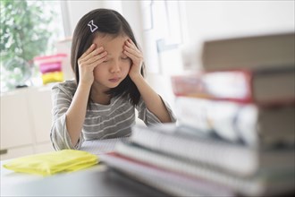 Anxious Chinese student rubbing forehead doing homework