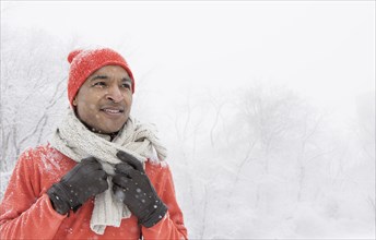 Black man wearing gloves and scarf in snow