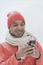 Black man using cell phone in snow