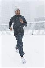 Black runner jogging in snow