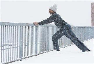 Black runner stretching in snow