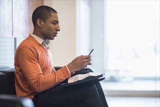 Black businessman using cell phone in office lobby