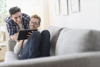 Caucasian gay couple using digital tablet on sofa