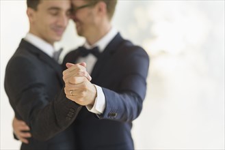 Caucasian gay grooms dancing at wedding