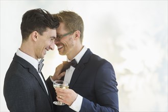 Caucasian gay grooms hugging at wedding
