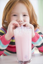 Caucasian girl blowing bubbles in strawberry milk