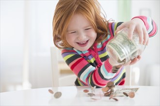 Caucasian girl pouring money from change jar