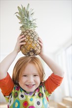 Caucasian girl balancing pineapple on head