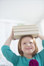 Caucasian girl balancing books on head