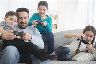 Caucasian father and children playing video games on sofa