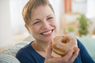 Smiling Caucasian woman eating donut
