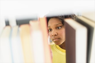 Black student choosing book from library shelf