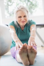 Older Caucasian woman stretching in gym