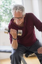 Older Caucasian man lifting weights in gym