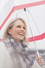 Older Caucasian woman standing under umbrella