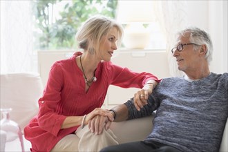 Older Caucasian couple talking in living room