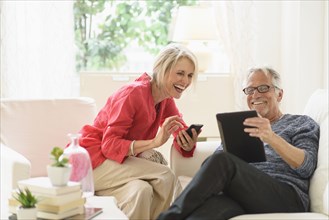 Older Caucasian couple using technology in living room