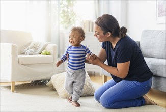 Mixed race mother playing with baby son in living room