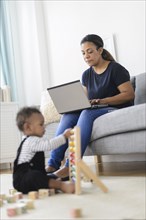 Mixed race mother and baby son relaxing in living room