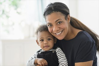 Mixed race mother holding baby son in living room