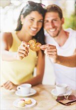 Hispanic couple sharing cookie at cafe