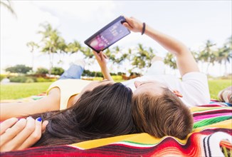 Hispanic couple using digital tablet on blanket in park