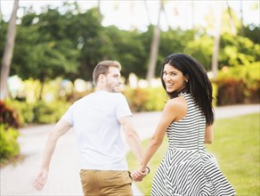 Smiling Hispanic couple walking in park