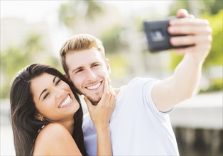 Hispanic couple taking selfie outdoors
