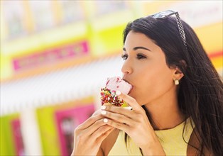 Hispanic woman eating ice cream cone outdoors