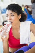Close up of woman drinking water bottle in gym