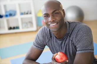 Black man eating apple in gym