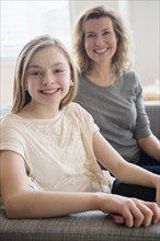 Caucasian mother and daughter smiling on sofa