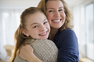 Caucasian mother and daughter hugging in living room